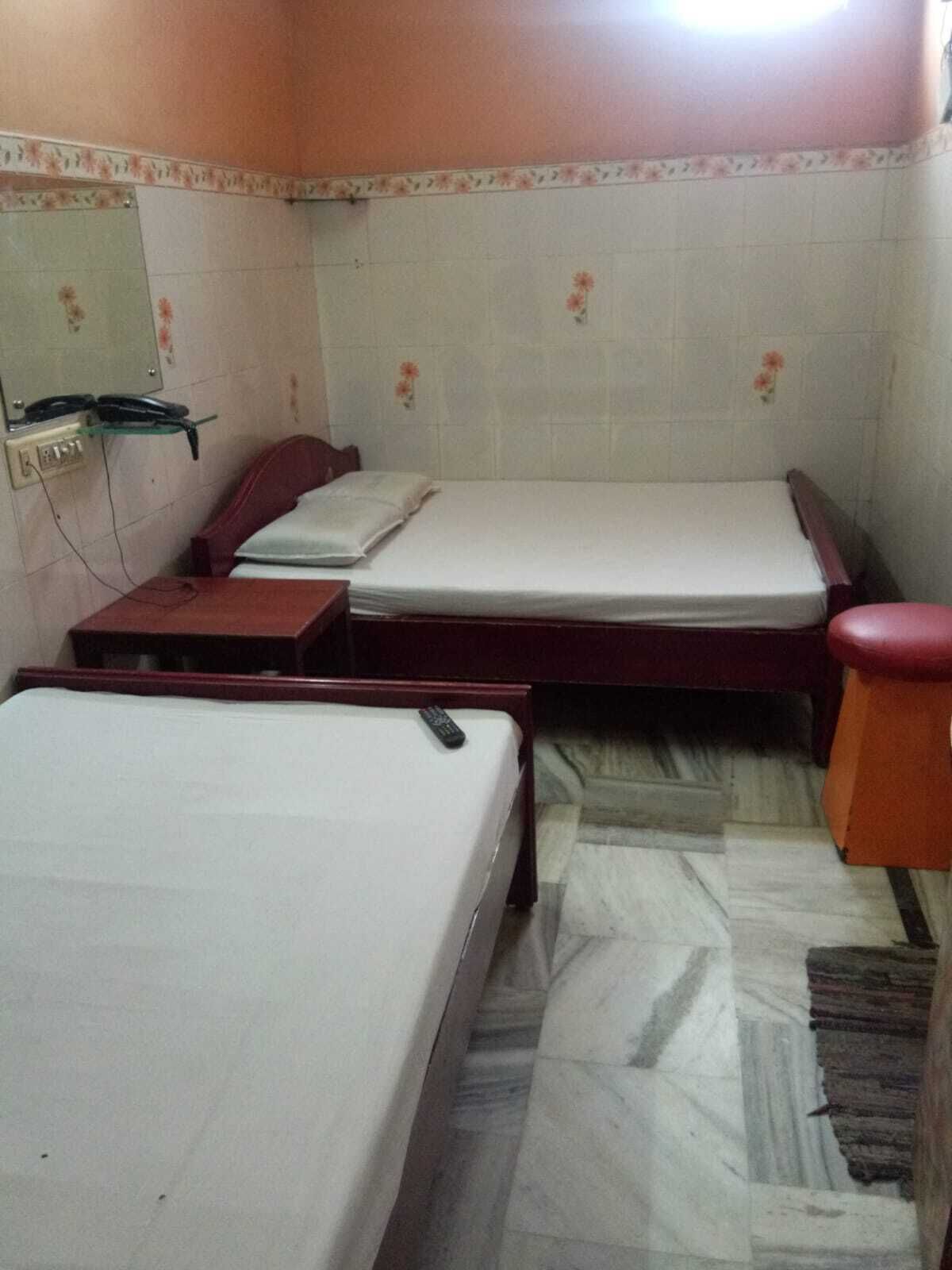 A room with two beds, a desk, a chair, and a small table.