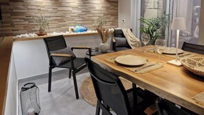 A dining area with a wooden table, chairs, and a stone wall. - Chrison modern house (Zakynthos)