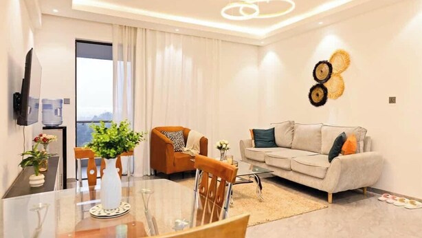 Una sala de estar moderna con un sofá, una mesa de comedor y un televisor en la pared.