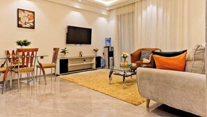 Una sala de estar moderna con sofá, mesa de centro, televisor y un comedor con sillas y mesa.