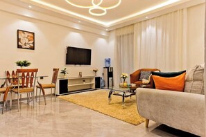 A modern living room with a sofa, coffee table, TV, and a dining area with chairs and a table. - Skyline views|pool|gym (Nairobi)