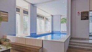 Un área de piscina interior moderna con vista despejada, escalones de madera y un letrero que indica que no está permitido bucear.