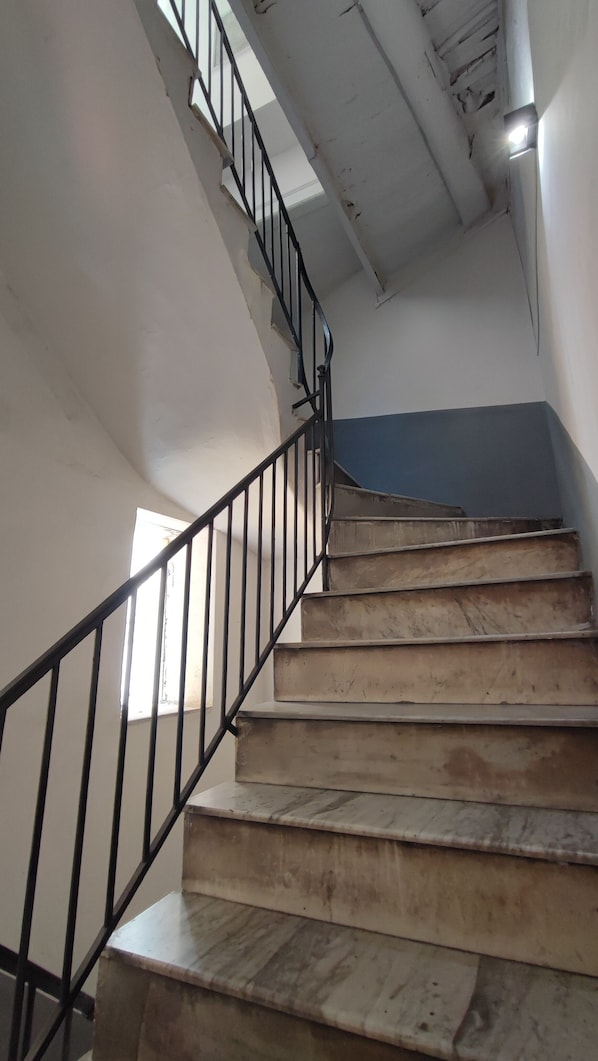 A staircase with a black metal railing and wooden steps. - Five Boutique Rooms (Naples)