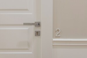 A white door with a silver handle and a keyhole, and a number '2' on the adjacent wall. - Five Boutique Rooms (Naples)