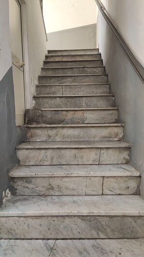A set of marble stairs leading upwards, with a handrail on one side and a plain wall on the other. - Five Boutique Rooms (Naples)