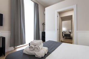 A hotel room with a bed, a TV, a desk, and a wardrobe. - Five Boutique Rooms (Naples)