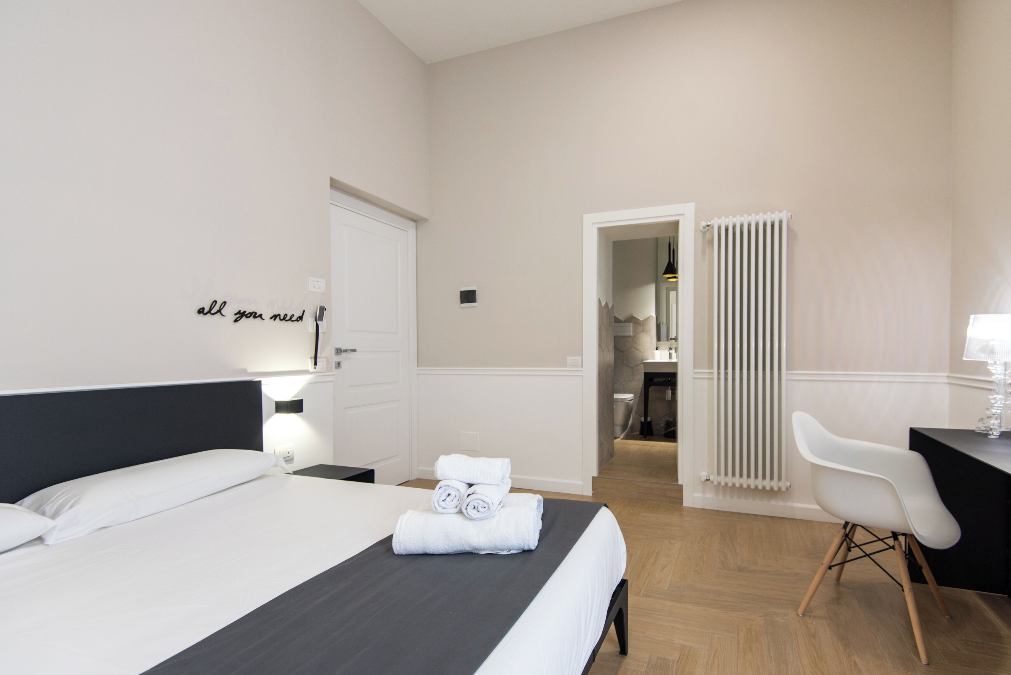 A hotel room with a bed, a desk, a chair, and a bathroom visible through an open door.