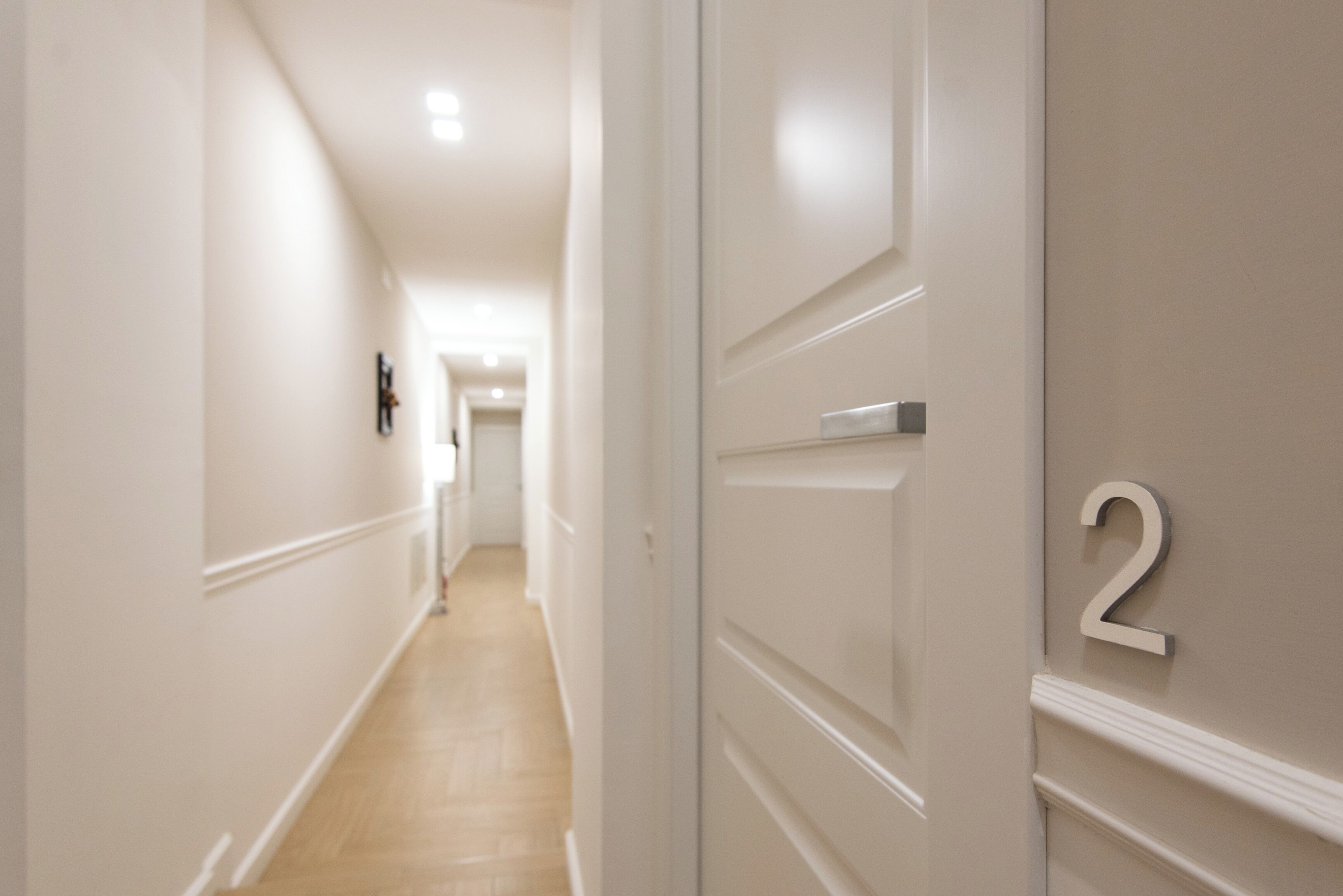 A hallway with a wooden floor, white walls, and a door with the number 2 on it.