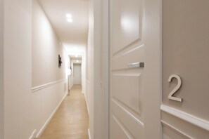 A hallway with a wooden floor, white walls, and a door with the number 2 on it. - Five Boutique Rooms (Naples)