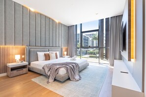 Ein modernes Schlafzimmer mit einem großen Bett, Nachttischen, einem Fernseher und Blick ins Freie.