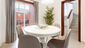Un coin repas avec une table ronde, des chaises, une plante en pot et un escalier.