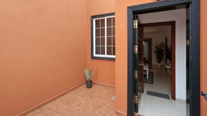 Un couloir avec une plante en pot, une fenêtre et une porte donnant sur un espace intérieur.