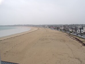 A beach with a long stretch of sand, a calm sea, and buildings along the shore. - Saphyr - Seaside apartment in Saint-Cast-le-Guildo (Saint-Cast-le-Guildo)