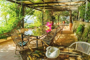 An outdoor dining area with a glass table, wicker chairs, and a swan-shaped centerpiece. - Complesso Villa Le Palme (Forio)