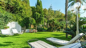 Un jardín con dos sillones de descanso, una mesa y un farol.