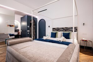 Una habitación de hotel moderna con una cama con dosel, un espejo grande, un armario empotrado y una mesita de noche pequeña.