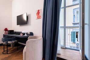 A modern living room with a flat-screen TV, a sofa, a small table, and a large window with curtains. - Via Port'Alba 19 (Naples)