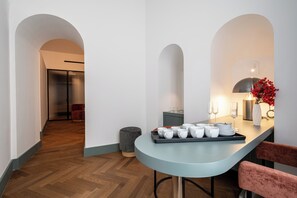 Una cocina moderna con una encimera curva, un comedor con una mesa azul claro y una silla roja.
