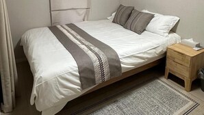 A single bed with a patterned bedspread, a bedside table with a tissue box, and a patterned rug on the floor. - Dc Sakura Hotel-HitomiHouse (Osaka)