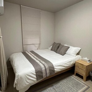 A single bed with a patterned bedspread, a bedside table with a tissue box, and a patterned rug on the floor. - Dc Sakura Hotel-HitomiHouse (Osaka)