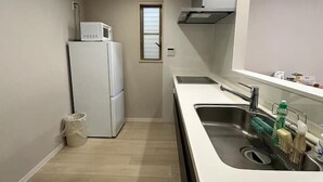 A compact kitchen with a refrigerator, microwave, and stainless steel sink. - Dc Sakura Hotel-HitomiHouse (Osaka)