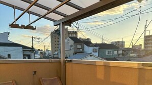 A balcony with wooden flooring, two wicker chairs, and a small table. - Dc Sakura Hotel-HitomiHouse (Osaka)