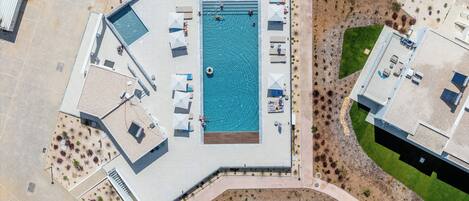 Vue aérienne d’un complexe hôtelier doté d’une piscine, de chaises longues et d’un jardin aménagé.