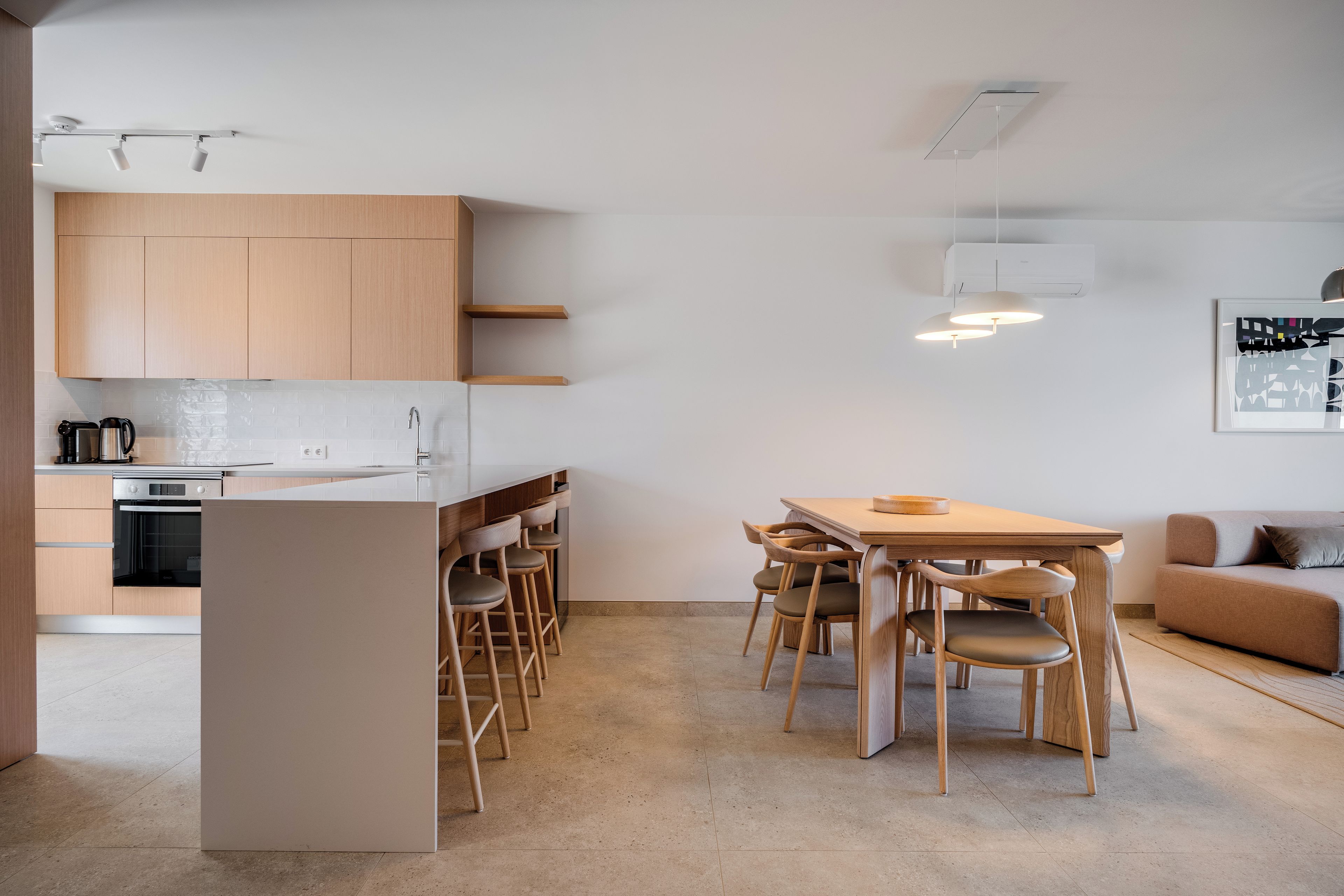 Une cuisine moderne avec des meubles en bois, un four encastré et un coin repas comprenant une table et des chaises.