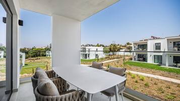 Uma sala de jantar moderna com mesa e cadeiras, vista para um bairro residencial e céu claro.