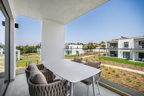 A modern dining area with a table and chairs, a view of a residential neighborhood, and a clear sky. - Prime Resorts - PrimeLife Carvoeiro (Carvoeiro)