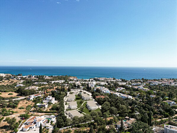 Un pueblo costero con edificios blancos, zonas verdes y una vista despejada del mar.