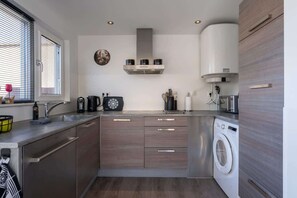 Eine moderne Küche mit Einbauwaschmaschine, Kaffeemaschine und Mikrowelle.