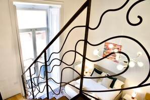 A bedroom with a bed, bedside lamps, a window, and a staircase with a decorative railing. - Via Tarsia 23 (Naples)