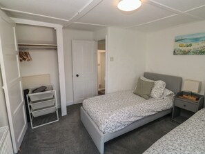 Un dormitorio con cama, mesita de noche, lámpara, armario y un cuadro en la pared.