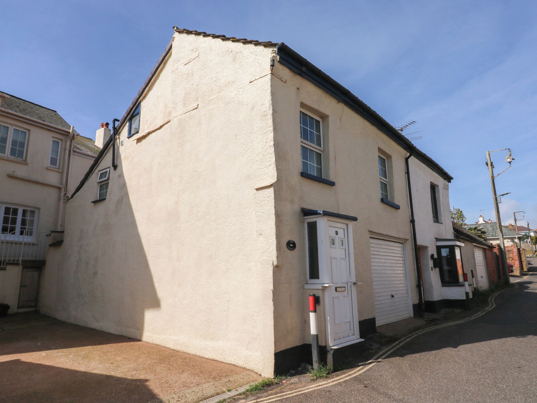 Un bâtiment d’un seul étage, à l’extérieur blanc, avec une porte de garage et un petit coffret électrique.