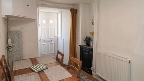 A dining room with a table, chairs, a radiator, a cabinet, and a door.