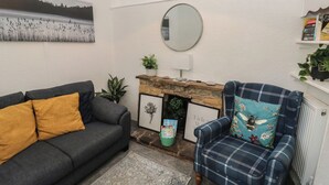 A living room with a sofa, armchair, fireplace, and a framed picture of a flower.