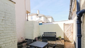 A patio with a table and chairs, a bench, and a potted plant. - The Cottage (Budleigh Salterton)