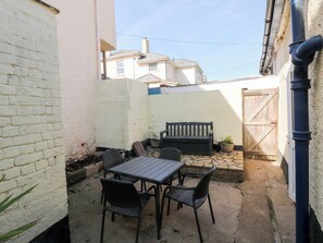 Un patio con una mesa, sillas, un banco y una planta en maceta.