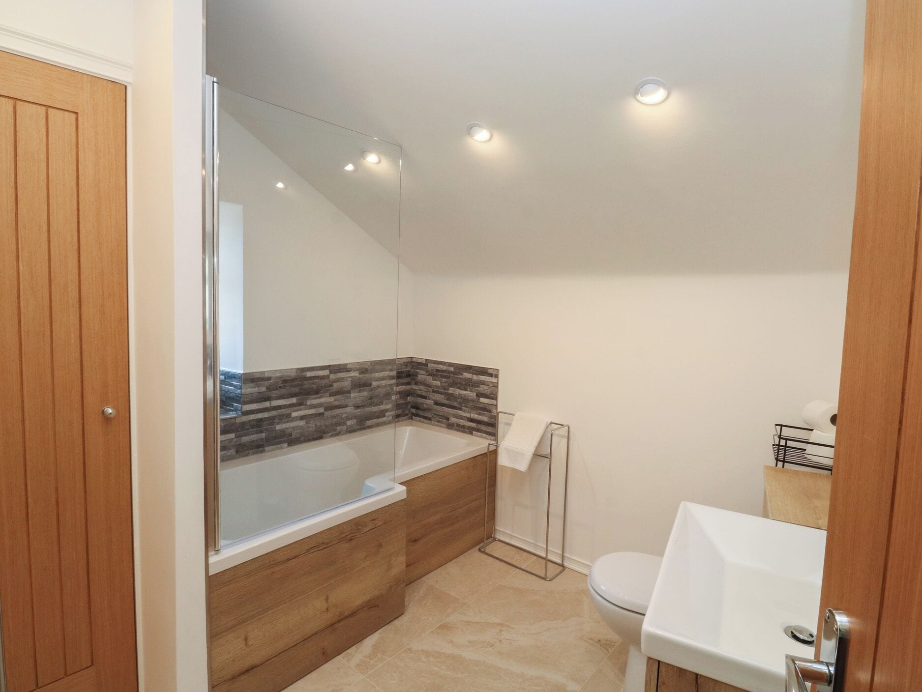 A modern bathroom with a glass-enclosed shower, a wooden vanity, a toilet, and a sink.