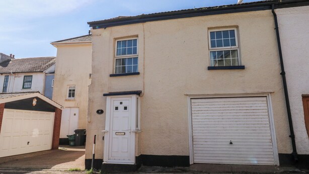 A two-story building with a garage, a white door, and a garage door.