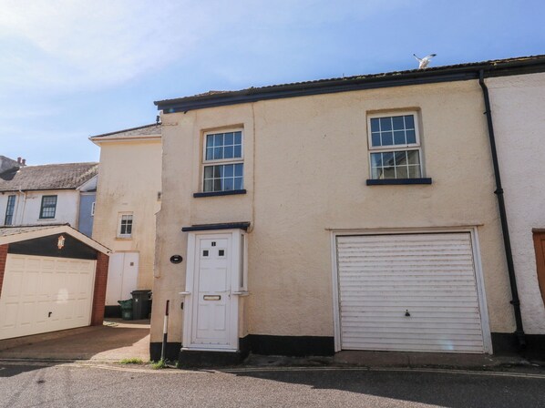 A two-story building with a garage, a white door, and a garage door.