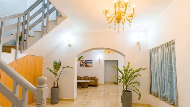 A spacious interior with a staircase, a chandelier, and potted plants. - Reebah Inn & Suites (Vagator)