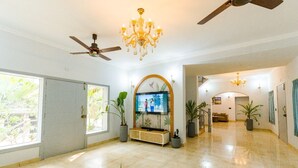 A spacious lobby with a ceiling fan, a TV mounted on a wall, and potted plants. - Reebah Inn & Suites (Vagator)