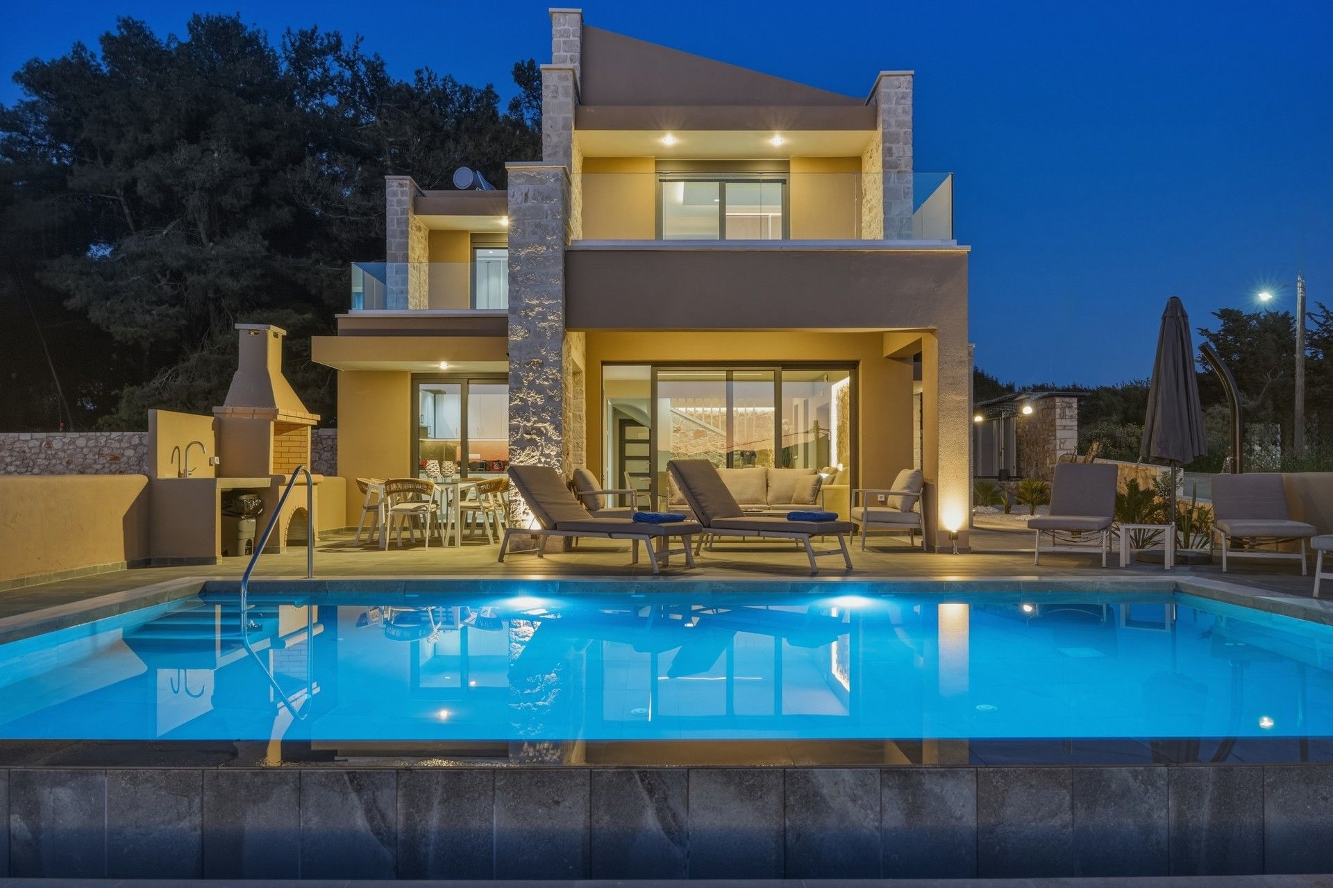 A modern two-story house with a swimming pool, outdoor seating, and a stone fireplace.