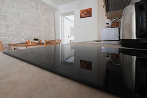 Eine Küche mit Steinwand, einem Esstisch mit Stühlen, einem Kühlschrank und einer Mikrowelle.
