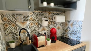 Una cucina con un lavandino nero, un tostapane rosso, un bollitore rosso e una pianta in vaso.