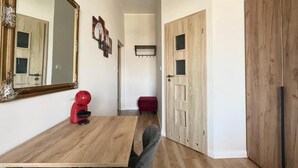 Una stanza con un tavolo da pranzo in legno, una sedia rossa, un grande specchio e un armadio.