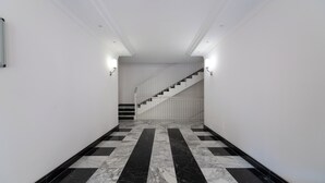 Ein Korridor mit einem schwarz-weißen Schachfußboden, weißen Wänden und einer Treppe mit weißer Geländer.