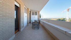 Ein Balkon mit Tisch und Stühlen, einer Tür und im Hintergrund der Blick auf einen Baukran.